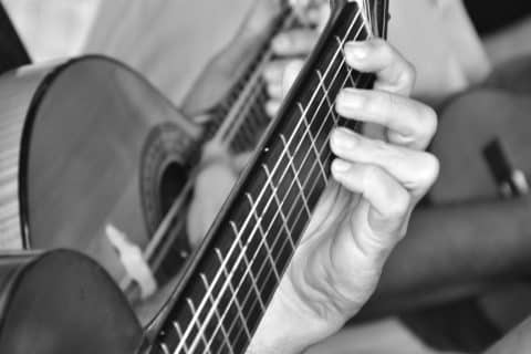 Músico tocando violão acústico em close, imagem simbólica sobre lançamentos de álbuns musicais previstos para 2026