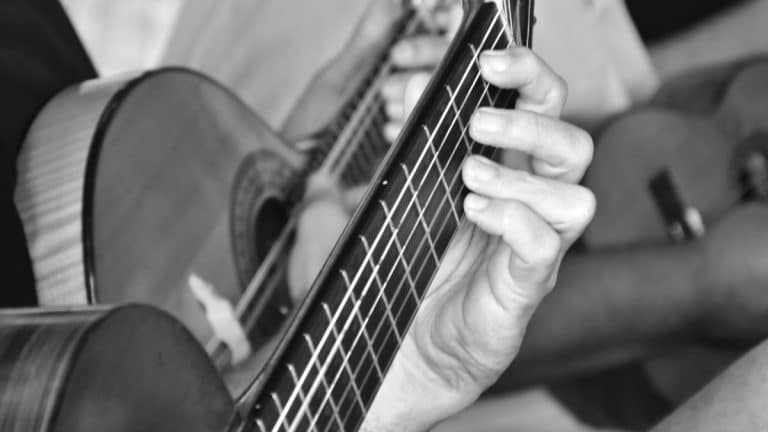 Músico tocando violão acústico em close, imagem simbólica sobre lançamentos de álbuns musicais previstos para 2026