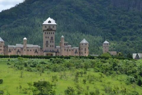 De polêmica política a centro de estética: Castelo Monalisa será resort de transplante capilar O icônico Castelo Monalisa, localizado em São João Nepomuceno (MG), está prestes a escrever um novo capítulo em sua história. A suntuosa propriedade, que pertenceu ao falecido ex-deputado Edmar Moreira, foi adquirida para se tornar um resort de luxo especializado em transplante capilar. A notícia foi revelada pelo novo dono do imóvel, o médico cirurgião plástico e dermatologista João Mansur. O objetivo é transformar o local em um complexo de saúde e bem-estar que une procedimentos médicos de alta tecnologia a uma experiência de hospedagem de alto padrão. O passado polêmico do "Castelo do Deputado" Construído na década de 90, o castelo ganhou as manchetes nacionais em 2006. Na época, Edmar Moreira, conhecido como o "deputado do castelo", foi alvo de investigações por não declarar o imóvel à Justiça Eleitoral. Enquanto o patrimônio era avaliado em cerca de R$ 20 milhões, o político havia registrado apenas um terreno de valor simbólico. Após a morte de Moreira em 2023, o castelo ficou sob responsabilidade de seu filho e permaneceu à venda por aproximadamente dois anos, com lances mínimos que partiam de R$ 30 milhões. A venda foi selada no último dia de 2025. Estrutura de Gigante: 280 campos de futebol de área Situado no distrito de Carlos Alves, na Zona da Mata mineira, o complexo impressiona pelos números. A área total equivale a mais de 280 campos de futebol e oferece uma infraestrutura que será totalmente adaptada para o setor de turismo médico. O que o novo resort oferecerá: Acomodações de luxo: 37 suítes equipadas com closet. Lazer e Estética: Parque aquático, jardins, chafarizes e uma adega subterrânea. Infraestrutura Comercial: Cozinha industrial, salões amplos e ar-condicionado central. Recuperação Integrada: Áreas destinadas ao pós-operatório com assistência médica especializada. Por que um resort de transplante capilar em Minas Gerais? A escolha estratégica do local levou em conta a logística. De acordo com João Mansur, a proximidade com o Aeroporto Regional da Zona da Mata é um diferencial para atrair pacientes de todo o Brasil e do exterior. "Nossa meta é iniciar as operações em até sete meses. Vamos gerar empregos locais, impulsionar a economia de São João Nepomuceno e oferecer um atendimento centralizado", afirmou o cirurgião. O projeto conta com o suporte financeiro do BNDES e incentivos da prefeitura local. Atualmente, a clínica Mansur opera em Juiz de Fora, realizando cerca de oito procedimentos diários. A expectativa é que a mudança para o castelo amplie significativamente essa capacidade. Próximos passos As reformas para adequação clínica e hoteleira devem começar imediatamente. A ideia é que o paciente entre no castelo para o procedimento e permaneça no local para o descanso e a recuperação, usufruindo de toda a área verde e da capela histórica do complexo.