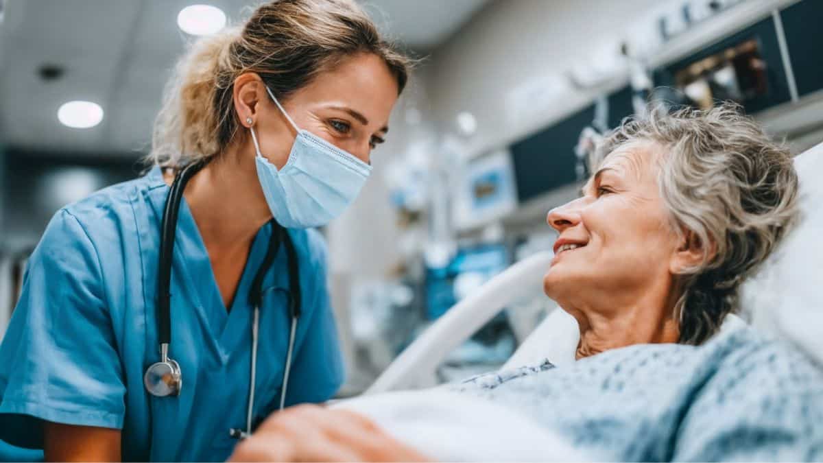 Profissional de enfermagem presta cuidados a paciente idosa em ambiente hospitalar.