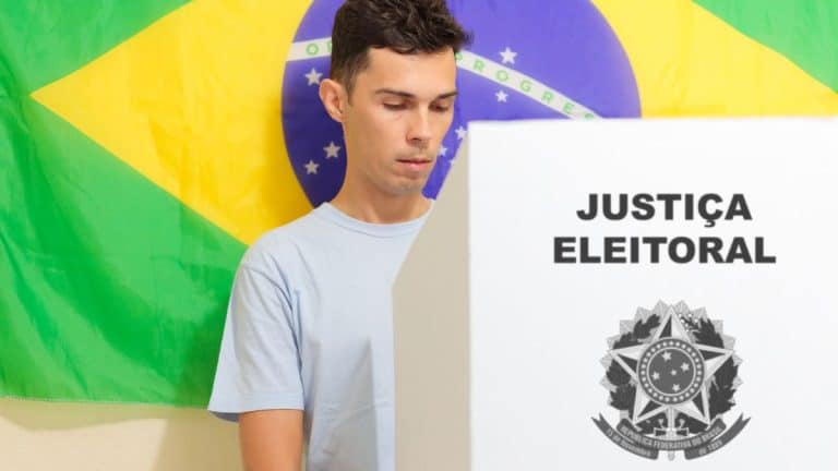 Eleitor vota em urna da Justiça Eleitoral com bandeira do Brasil ao fundo, imagem ilustrativa sobre ano eleitoral e mudanças no governo federal