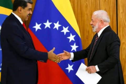 Presidente Lula cumprimenta Nicolás Maduro durante encontro oficial, com bandeiras do Brasil e da Venezuela ao fundo