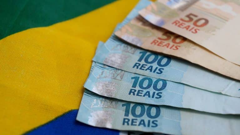 Cédulas de real sobre a bandeira do Brasil ilustram mudanças nas regras do PIS/Pasep em 2026