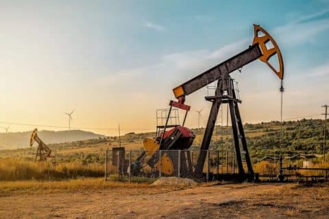 Bomba de extração de petróleo em campo petrolífero da Venezuela, com paisagem rural ao fundo e infraestrutura energética visível.