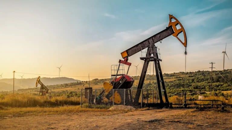 Bomba de extração de petróleo em campo petrolífero da Venezuela, com paisagem rural ao fundo e infraestrutura energética visível.